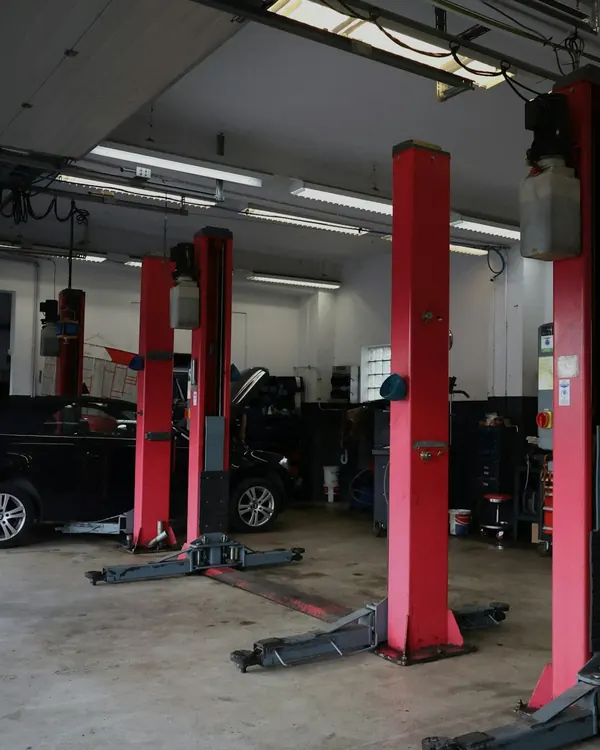 L’atelier : quatre ponts élévateurs rouges sur le sol en béton, une voiture en attente au fond