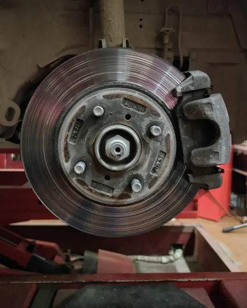 Un disque de frein et son étrier, roue démontée, sur un pont rouge